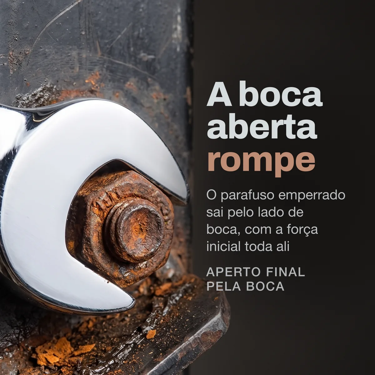 Close da boca aberta da chave encaixada em um parafuso enferrujado, com lasca de ferrugem e reflexo do aço cromado.